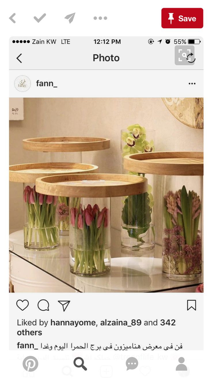 two vases filled with flowers sitting on top of a glass table next to each other