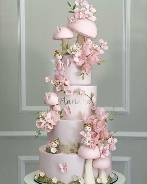 a three tiered cake decorated with pink flowers and mushrooms