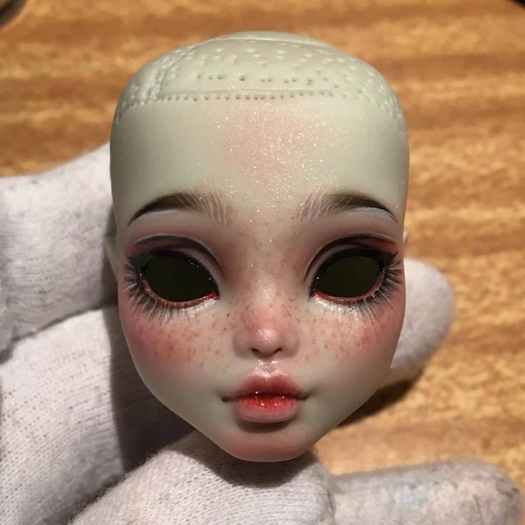 a close up of a doll with very large black eyes and an alien like head