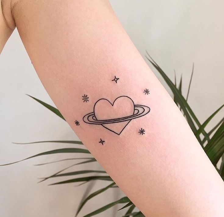 a heart tattoo on the arm with stars and saturn in the sky above it,