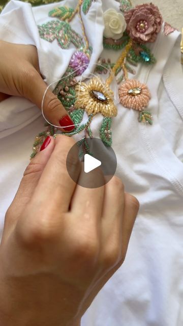 a woman is working on an embroidered shirt