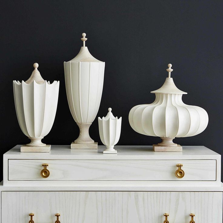 three white vases sitting on top of a chest of drawers next to each other