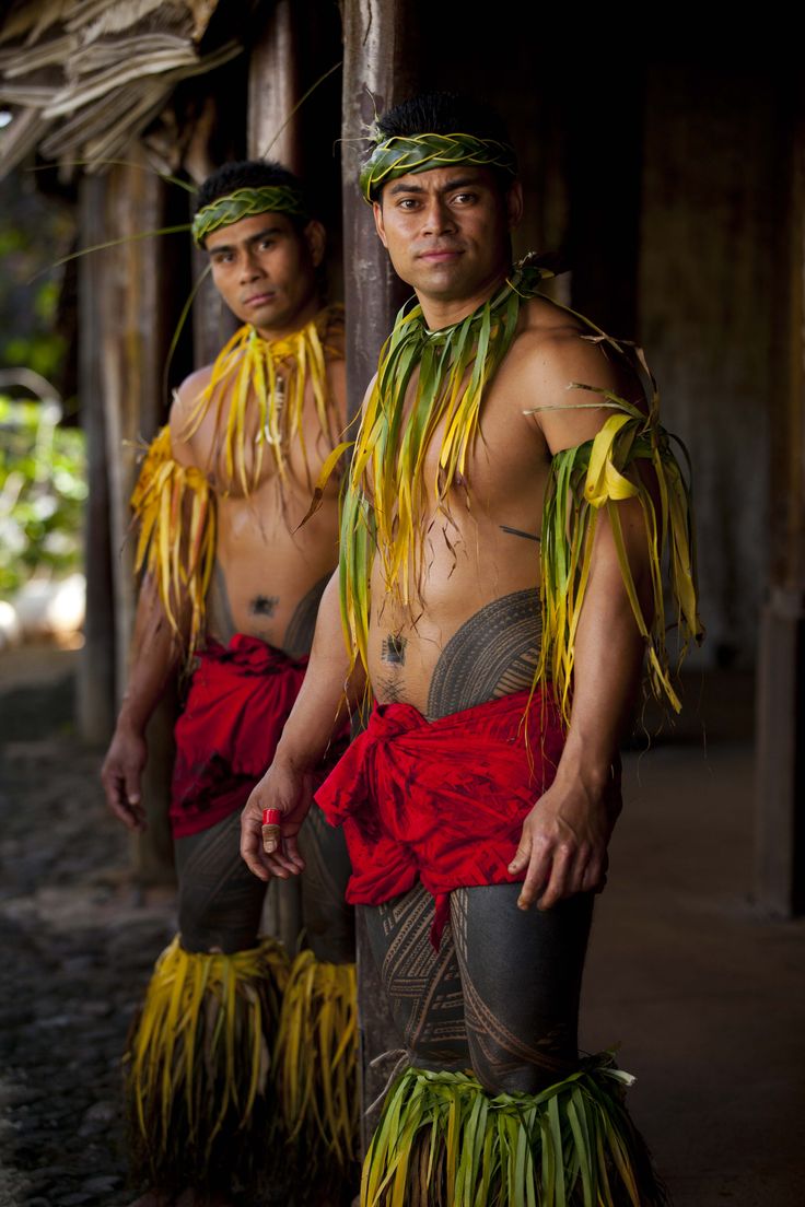 two young men dressed in grass skirts and headdresses, standing next to each other