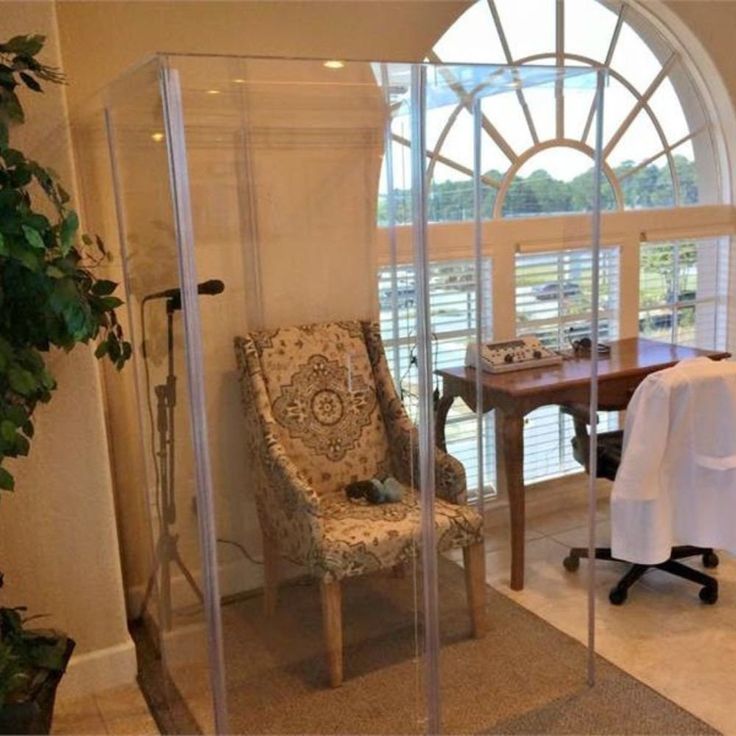 a room with a chair, table and shower stall in it's center area