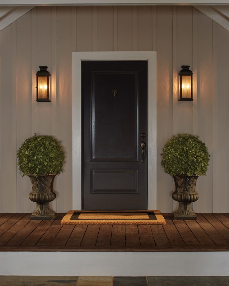 two potted plants sit on the front porch of a house with an entryway