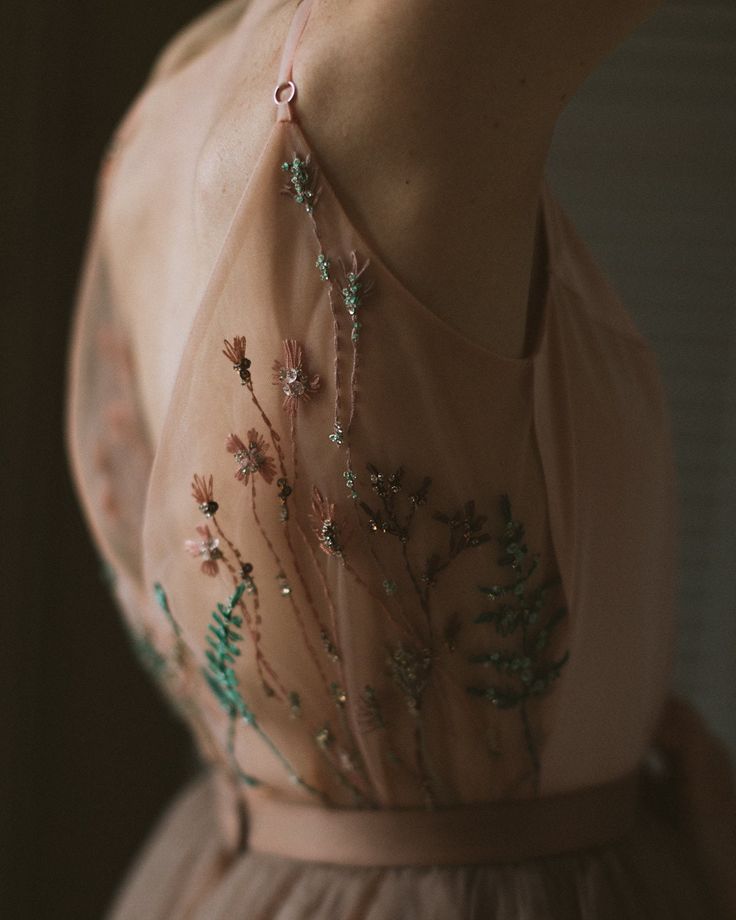 a woman wearing a pink dress with flowers on it's chest and neckline