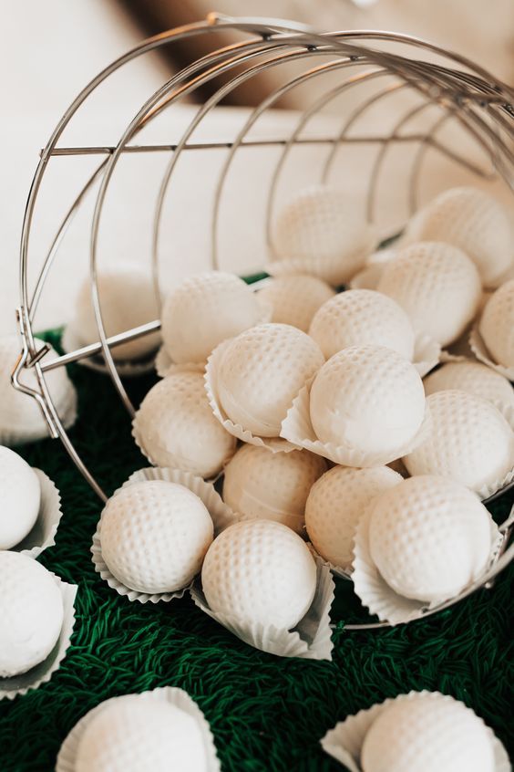 white golf balls in a metal basket on green grass