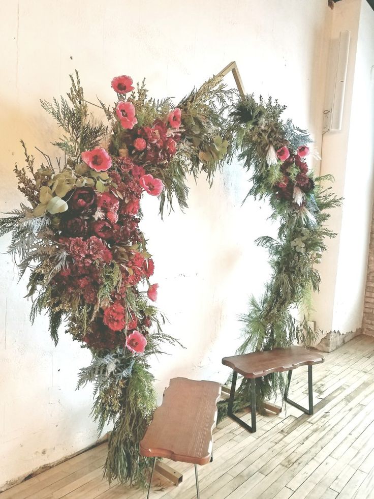 a wooden bench sitting in front of a floral arch