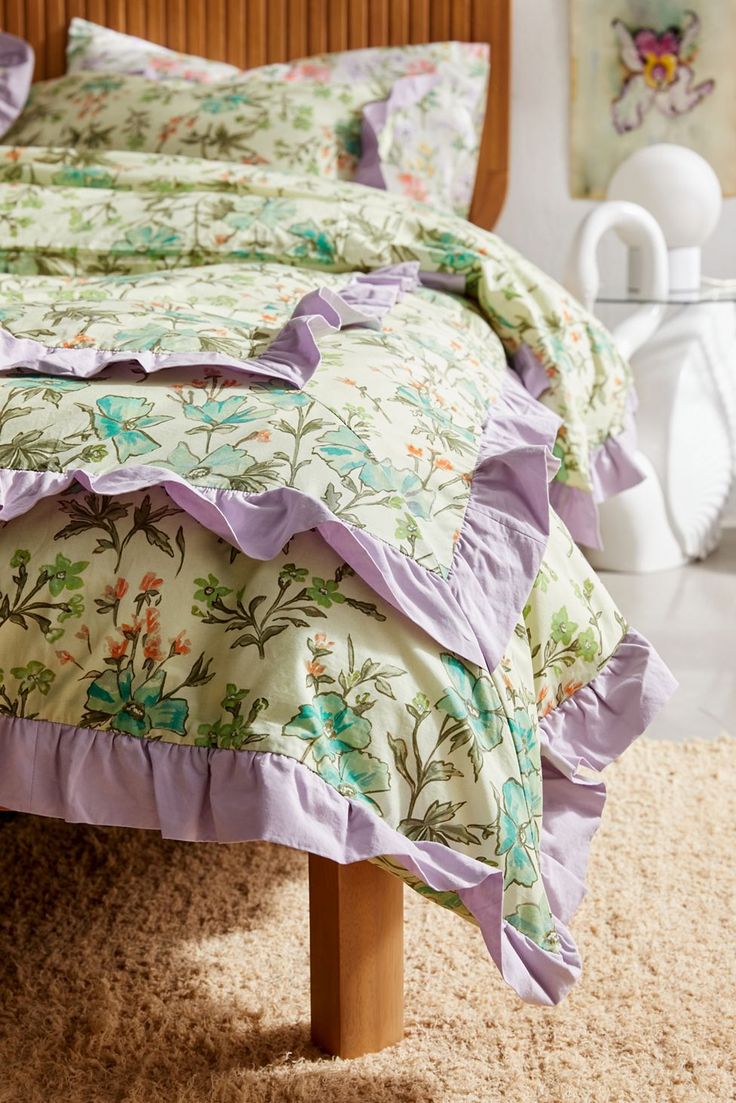 a bed with purple ruffled bedspread and matching pillow cases in a bedroom