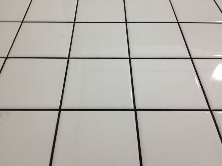 a white tiled floor with black grout