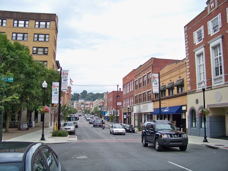 cars are driving down the street in front of buildings and trees on either side of the road