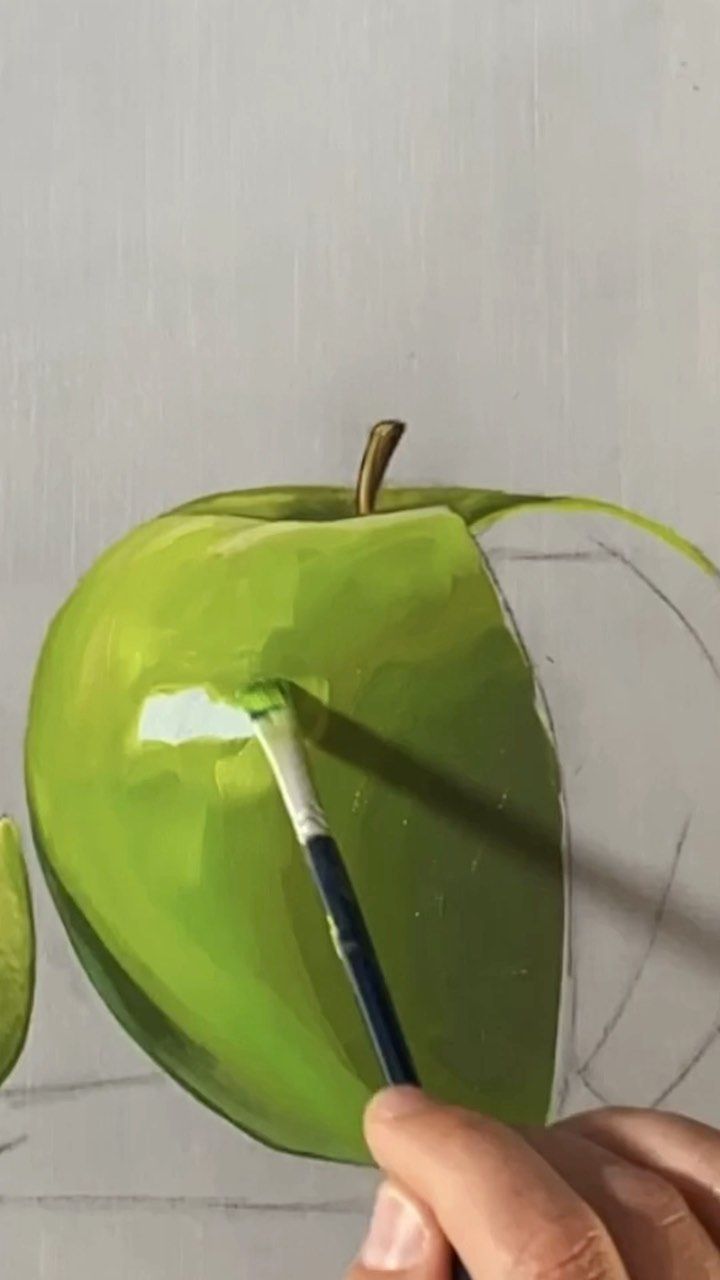 a person is painting an apple on the wall with a paintbrush and watercolor pencils