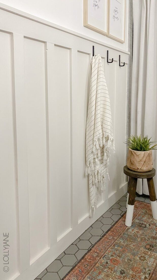 a bathroom with a rug, potted plant and white towels hanging on the wall