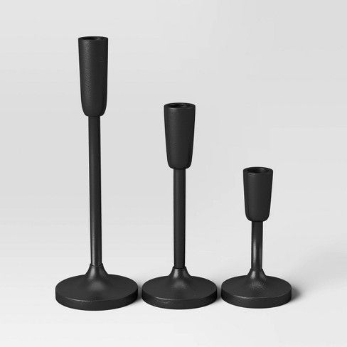 three black candlesticks and one candle holder