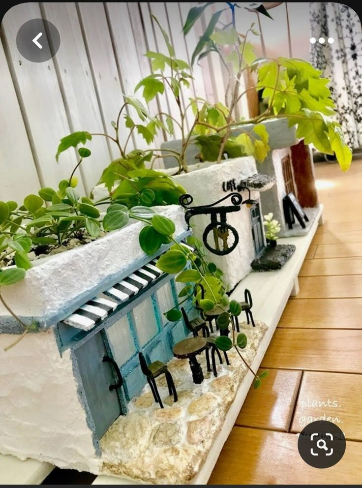 some plants are growing out of the top of a house shaped planter in front of a window