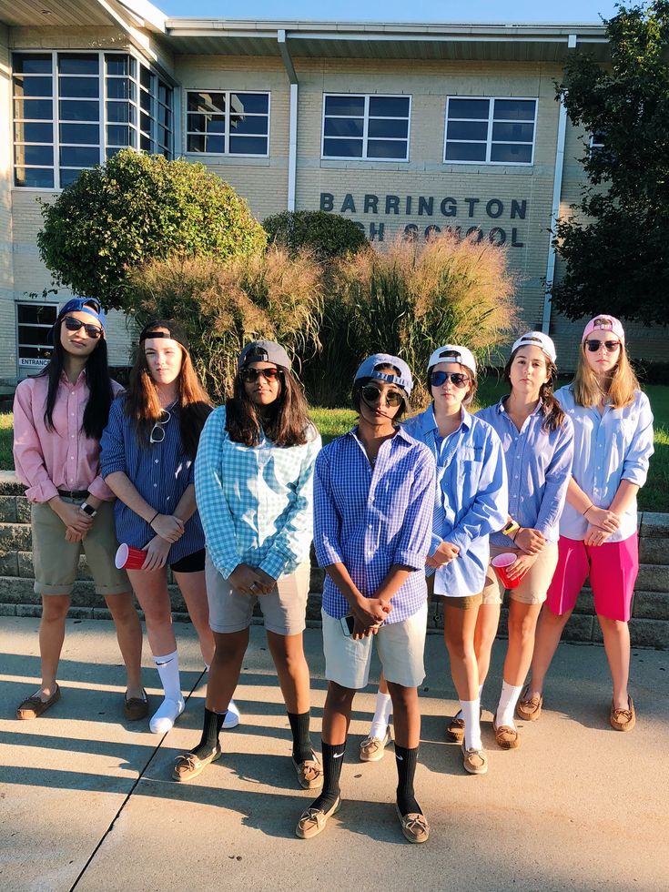 a group of young people standing in front of a building with sunglasses on their heads