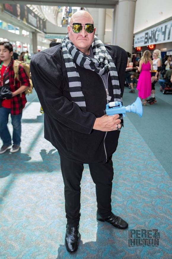 a man dressed in black and white is holding a blue object while people are walking around