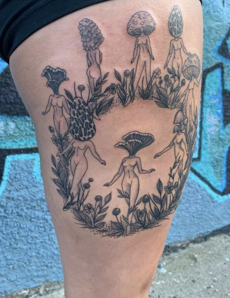 a woman's thigh with tattoos on it and mushrooms in the middle of her leg