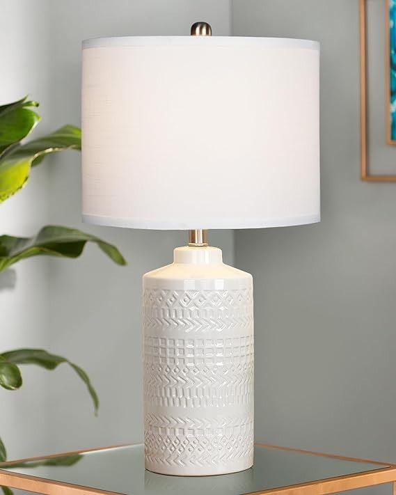 a white lamp sitting on top of a table next to a potted green plant