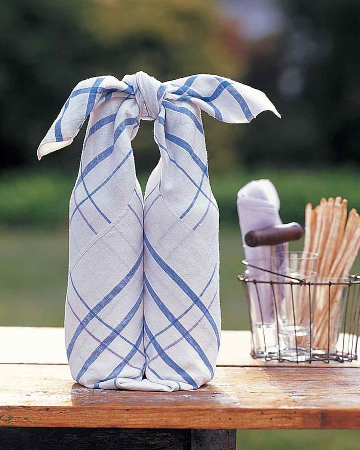 two kitchen towels tied together on a table with utensils in the back ground