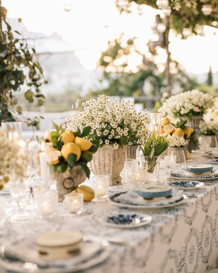 the table is set with lemons and white flowers