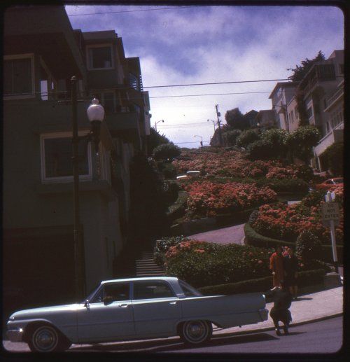 an old car is parked on the side of the road in front of some houses