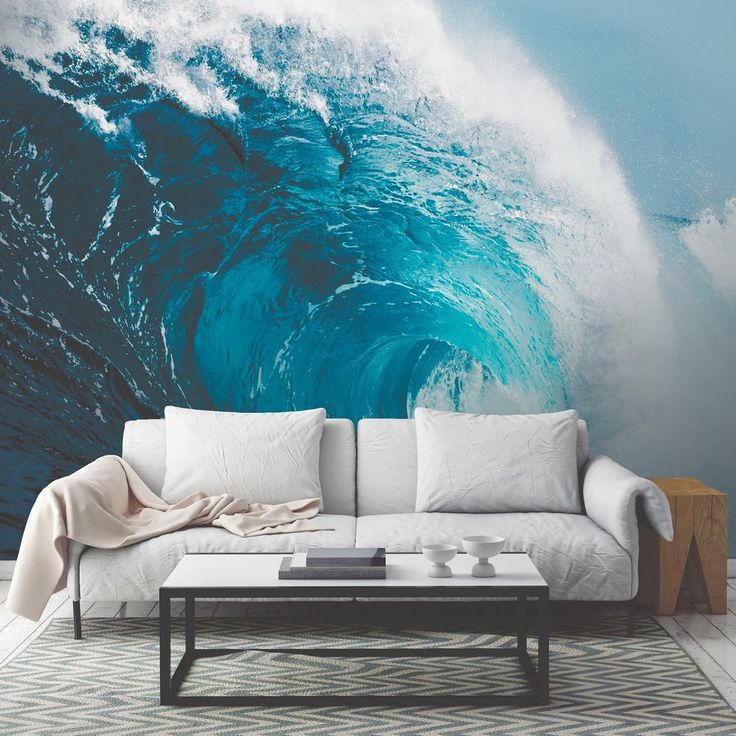 a couch sitting in front of a wall with a large blue wave coming out of it