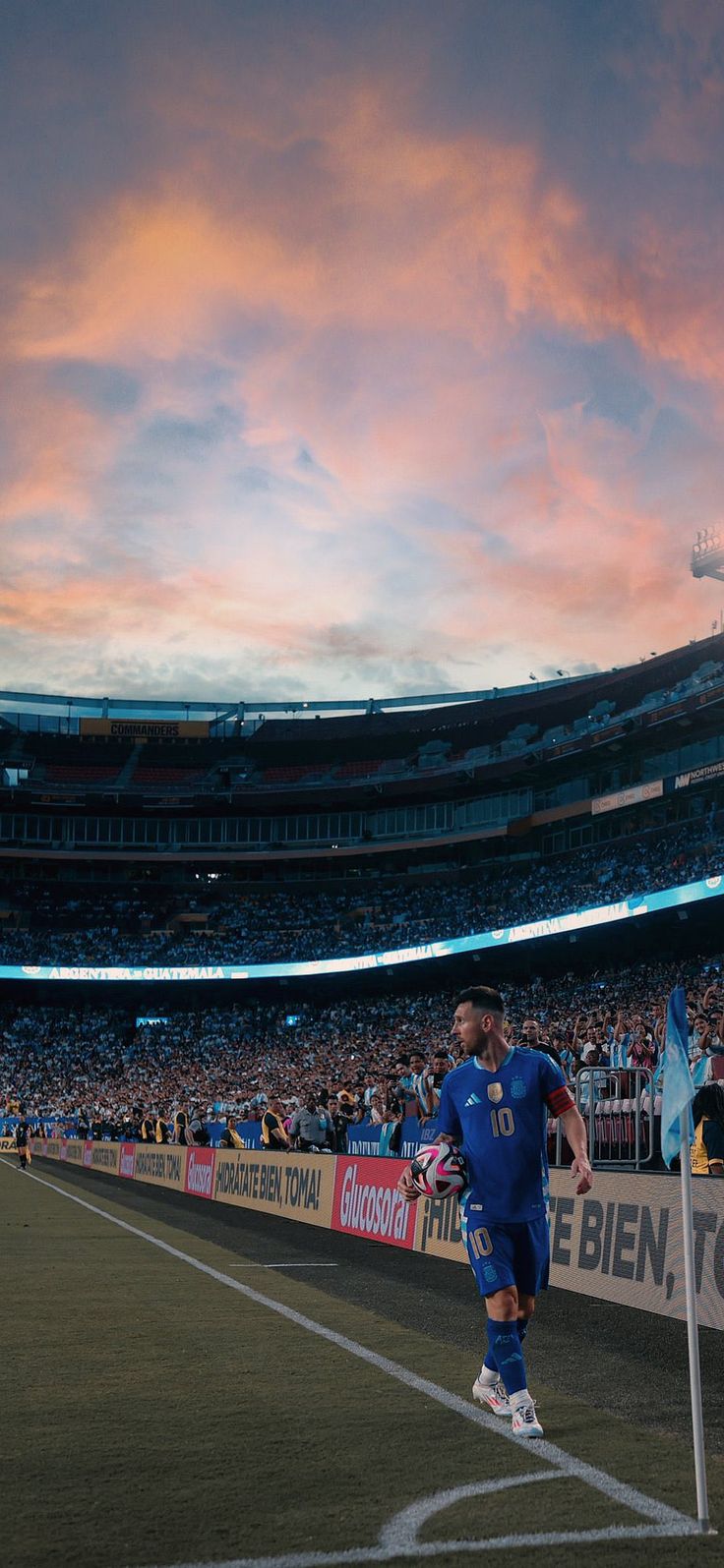 a soccer player is walking off the field at sunset in front of an empty stadium