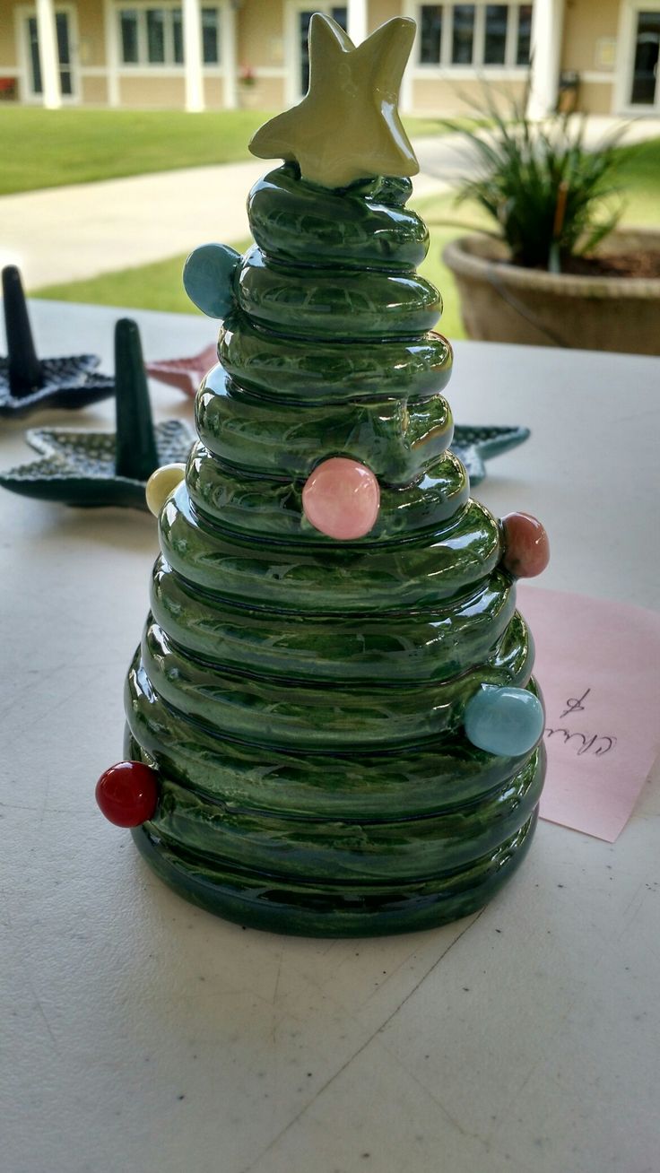 a green glass christmas tree sitting on top of a table next to a post it note