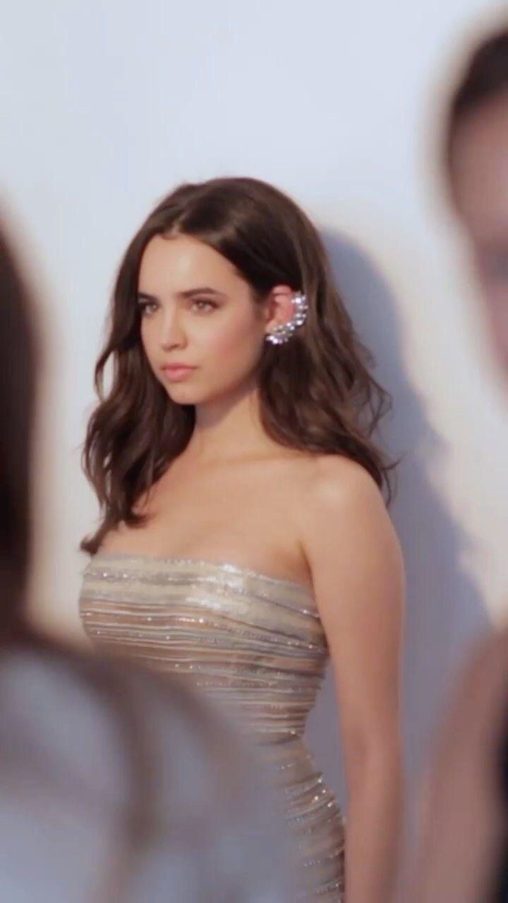 a woman in a strapless silver dress is looking at the camera with her hand on her hip