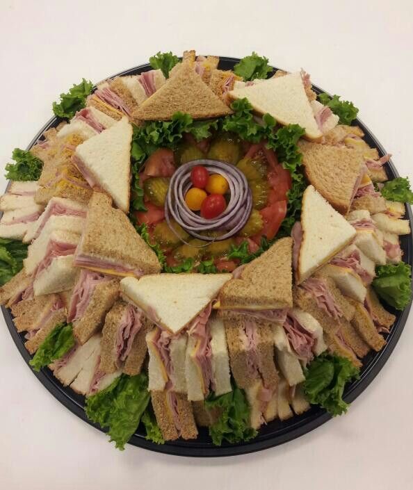 a black plate topped with lots of sandwiches and meats on top of lettuce