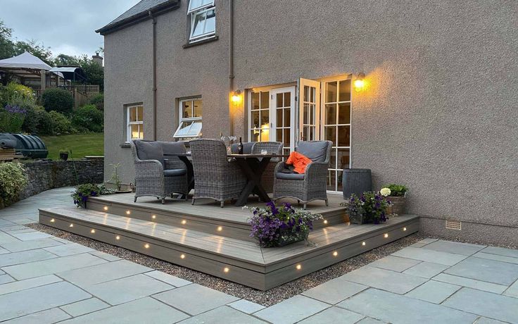 an outdoor patio with lights on the steps and seating area next to it, in front of a house