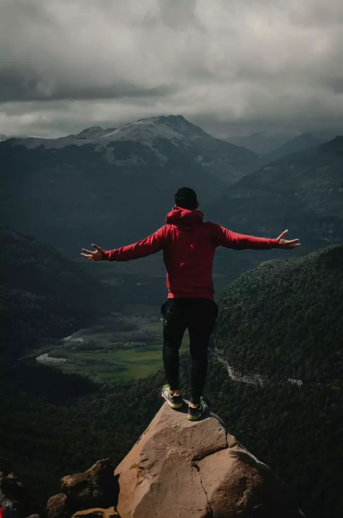 a man standing on top of a rock with his arms outstretched