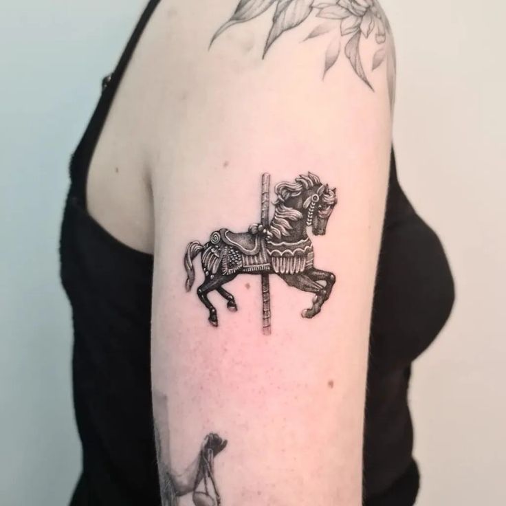 a black and white photo of a woman's arm with a horse on it