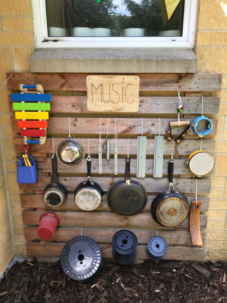 a wooden wall with pots and pans hanging from it's sides, next to a window