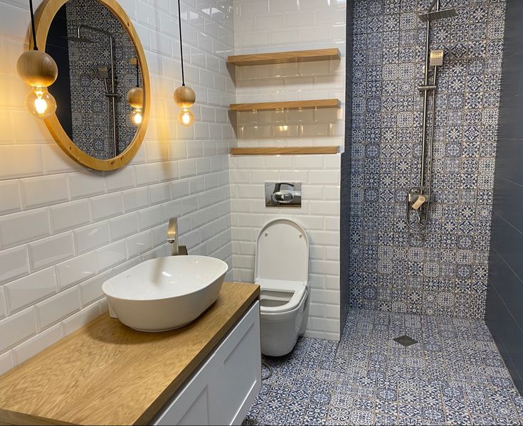 a white toilet sitting next to a walk in shower under a bathroom mirror and sink