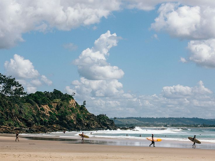 several surfers are walking on the beach with their surfboards