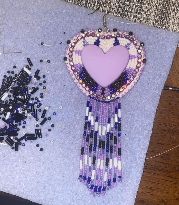 a purple heart shaped brooch sitting on top of a table next to other beads