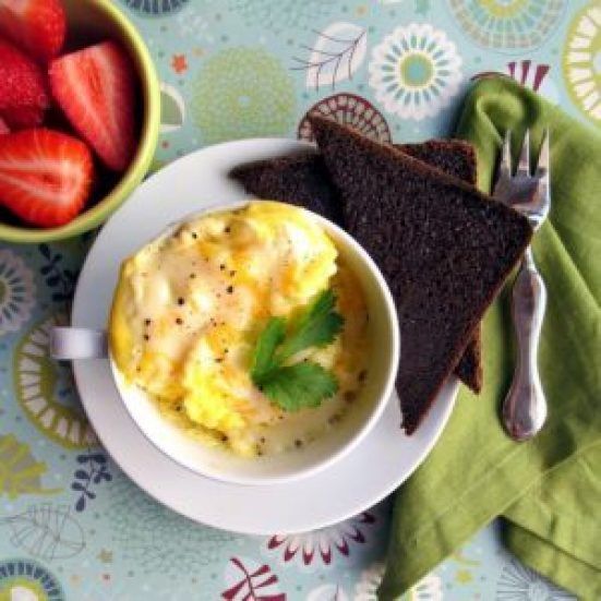 there is a bowl of eggs and toast on the table with strawberries next to it