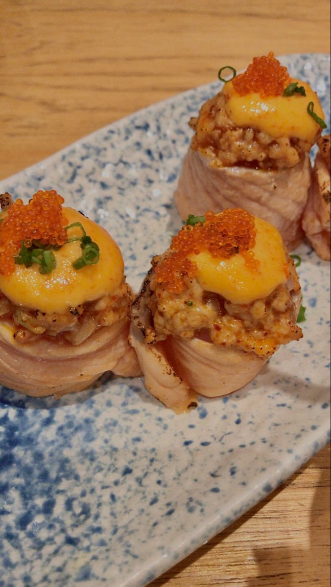 four pieces of sushi on a blue and white plate with garnishes