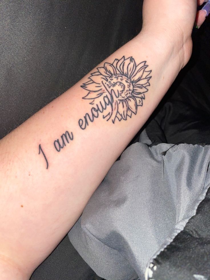 a person with a sunflower tattoo on their arm that says i am enough,