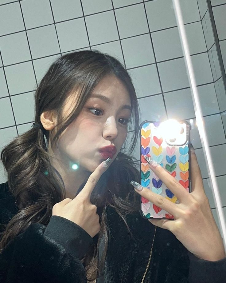 a woman taking a selfie in front of a bathroom mirror with her phone up to her face