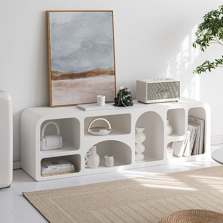 a living room with white furniture and a large painting on the wall above it's bookshelf