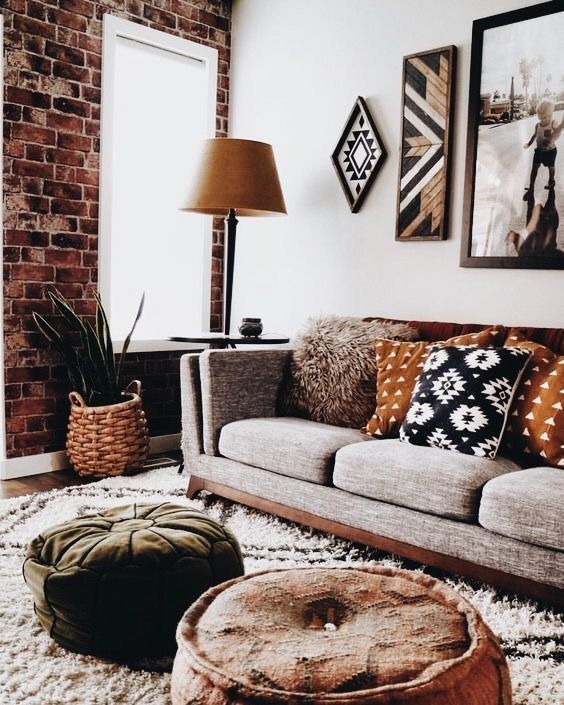 a living room filled with furniture next to a brick wall and floor lamp on top of a rug