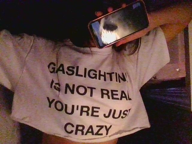 a person taking a photo with their cell phone while wearing a t - shirt that says, gaslightin is not real you're just crazy