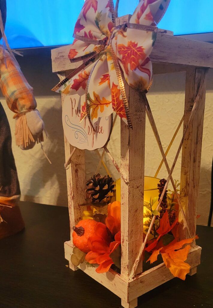 a small wooden lantern decorated with fall decorations