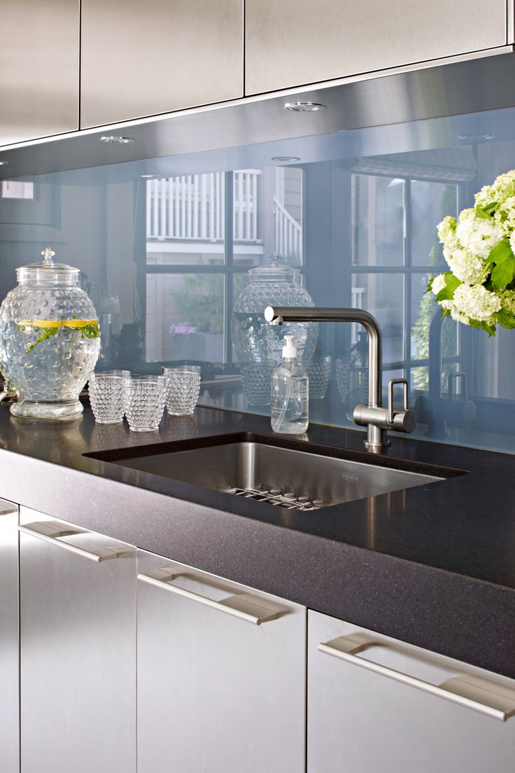 a kitchen sink sitting under a window next to a vase with white flowers in it