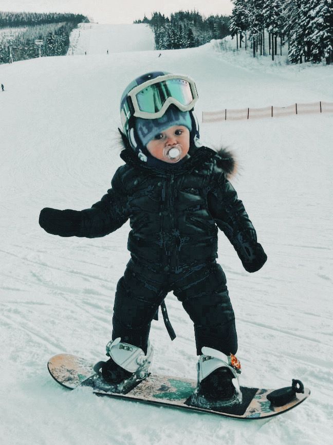 a small child on a snowboard in the snow