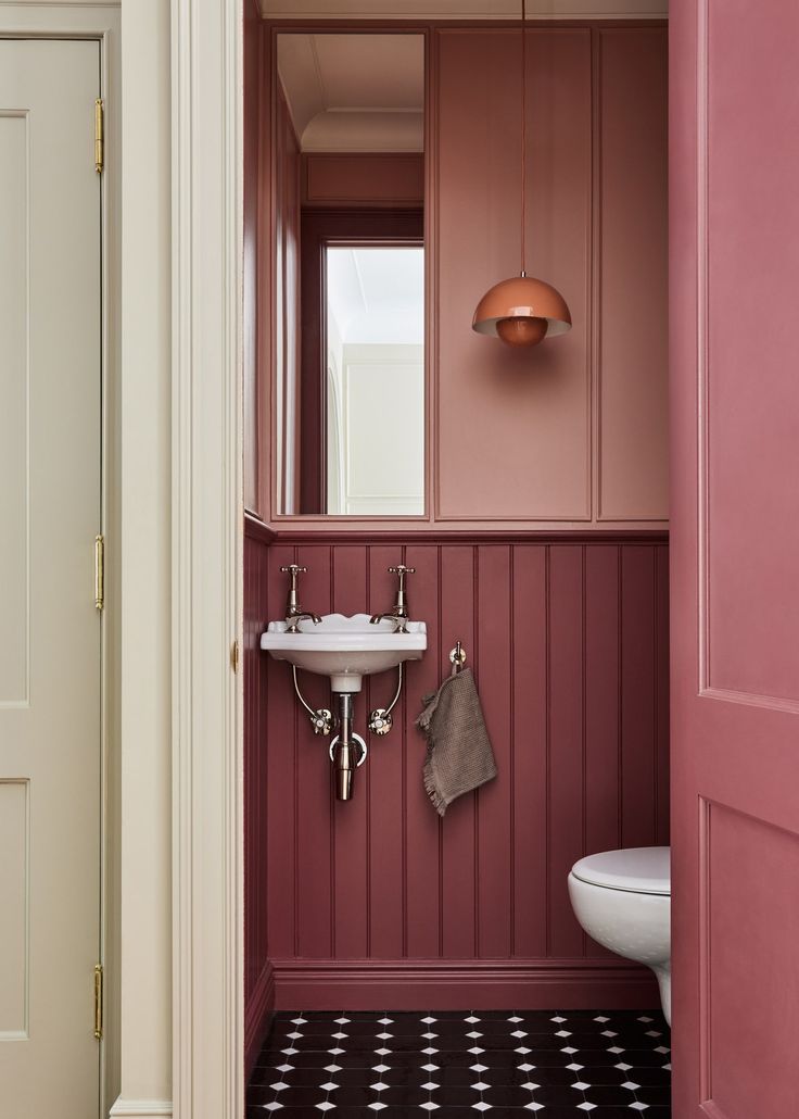 a bathroom with pink walls and black and white flooring is pictured in this image