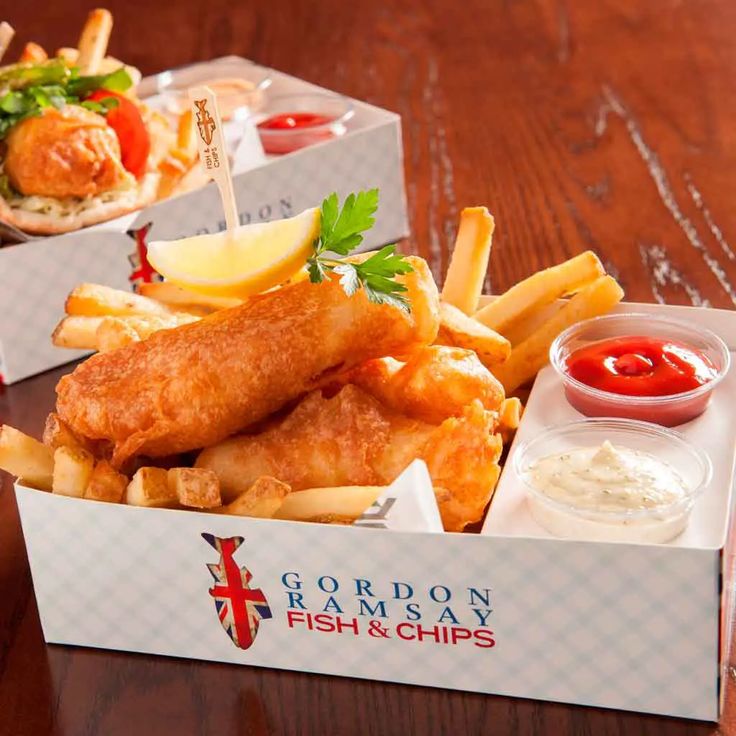 fish and chips with ketchup on the side in a box sitting on a table